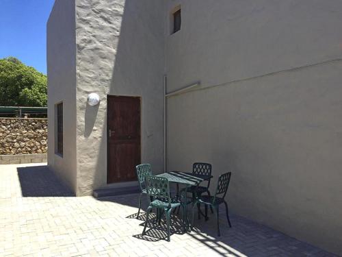 a patio with a table and chairs next to a building at 8 On Main in Witsand