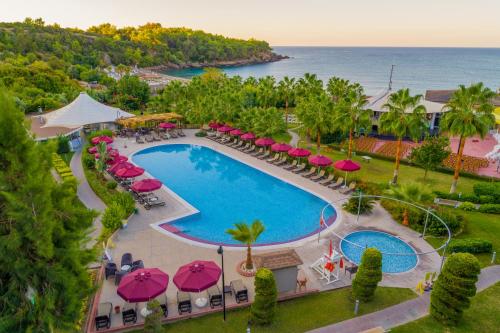 een luchtzicht op een zwembad met roze parasols en de oceaan bij Justiniano Deluxe Resort in Okurcalar