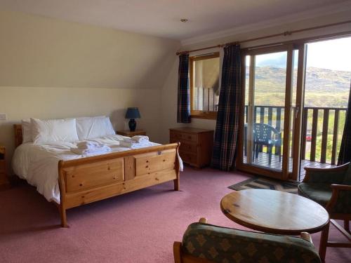 a bedroom with a bed and a table and a balcony at Ghillies Lodge Crianlarich in Crianlarich