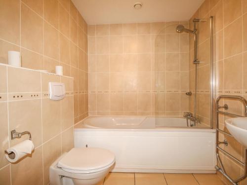 a bathroom with a toilet and a tub and a sink at Broadleys in Swanage