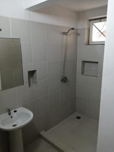 a white bathroom with a sink and a shower at Surf House Hostel in Santa Maria