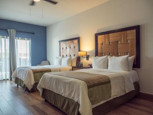 a hotel room with two beds and a window at Sawari Hotel in San Carlos