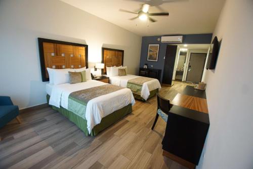 a hotel room with two beds and a desk at Sawari Hotel in San Carlos
