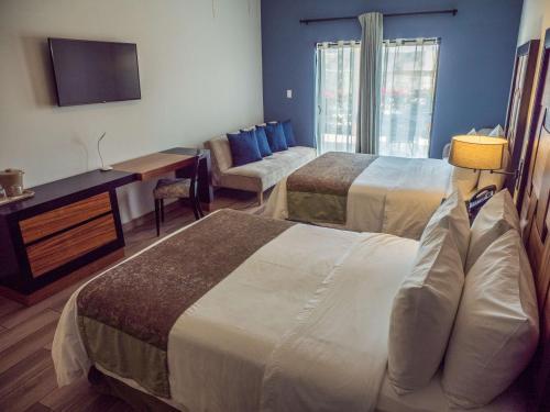 a hotel room with two beds and a flat screen tv at Sawari Hotel in San Carlos