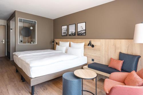 ein Hotelzimmer mit einem Bett und einem Stuhl in der Unterkunft aja Garmisch-Partenkirchen in Garmisch-Partenkirchen
