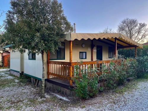 a small house with a porch and a tree at Toskana-Viareggio-Chalet-Zona-Rosa-1-mit-Klimaanlage-und-Wlan in Viareggio
