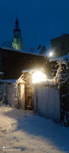 a building covered in snow with a lighthouse in the background at Noclegi Szymrych in Chełmsko Śląskie