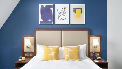 a bedroom with blue walls and a bed with yellow pillows at voco Grand Central Glasgow by IHG in Glasgow