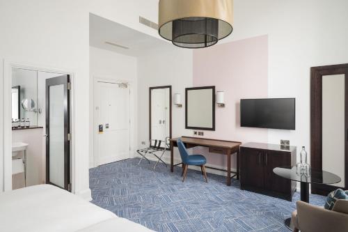 a hotel room with a desk and a tv at voco Grand Central Glasgow by IHG in Glasgow
