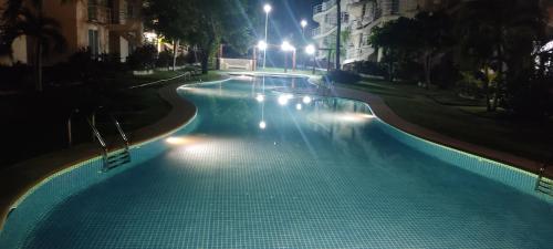 an empty swimming pool at night with lights at depto relajante Diamante in Acapulco