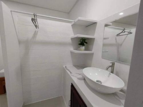 a white bathroom with a sink and a mirror at King Fa House in Mae Sot