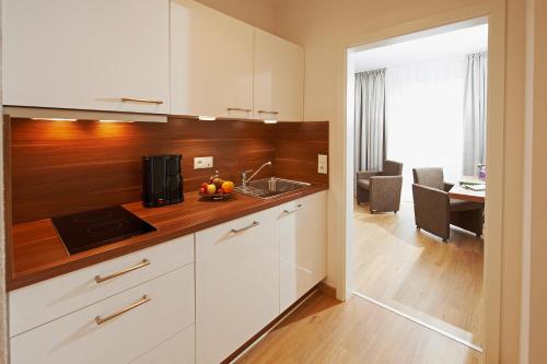 uma cozinha com armários brancos e uma bancada em Hotel Nordwind em Langeoog