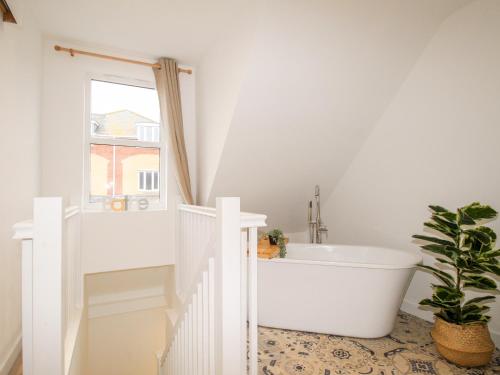 een witte badkamer met een bad en een raam bij Portside in Weymouth
