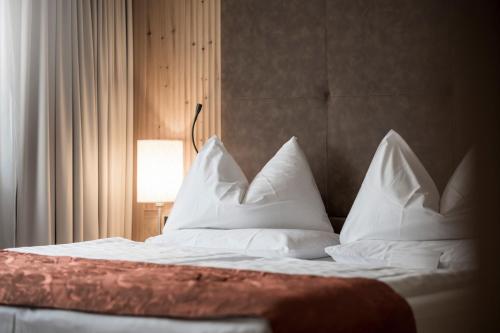 a bed with a white comforter and pillows at Adler Spa Resort Dolomiti in Ortisei