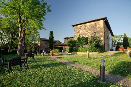 a building with a park with benches in the grass at Borgo La Casaccia in Montaione
