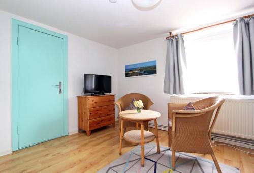 a living room with a table and chairs and a television at Haus-Atlantis-Whg-2-Duenenblick in Hörnum