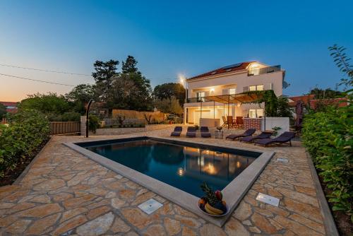 a swimming pool in front of a house at Apartments Luka & Lorena in Galovac