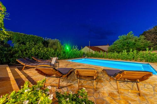 a group of chairs and a swimming pool at night at Apartments Luka & Lorena in Galovac