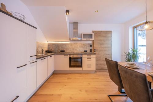 a kitchen with white cabinets and a wooden table at Apartment Mountainview in Neustift im Stubaital