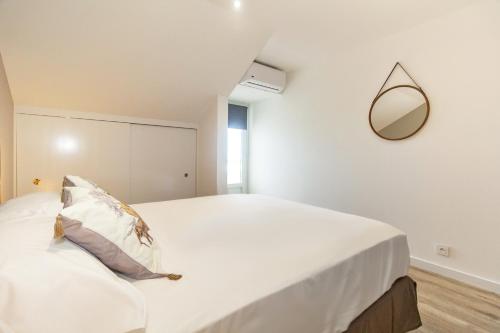 a bedroom with a large white bed with a mirror at Cap Noir - magnifique vue mer - St Gilles centre in Saint-Gilles les Bains