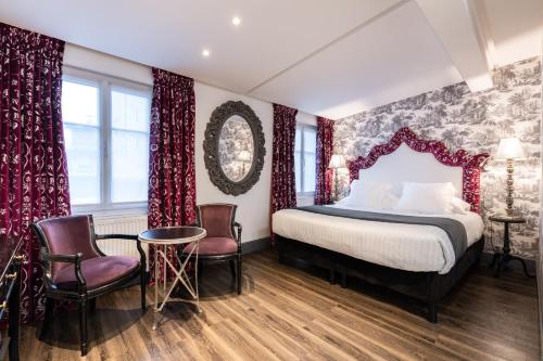 Schlafzimmer mit einem Bett mit roten Vorhängen und Stühlen in der Unterkunft Villa Glamour in Paris
