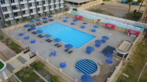 uma vista superior para uma piscina com cadeiras e guarda-sóis em Jewel Assiut Hotel em Assiut