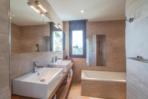 ein Badezimmer mit zwei Waschbecken und einer Badewanne und einem Spiegel in der Unterkunft Villa Velazquez Canyelles Almadrava - Immo Barneda in Roses