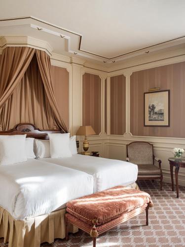 a hotel room with two beds and a chair at Hotel Fenix Gran Meliá - The Leading Hotels of the World in Madrid