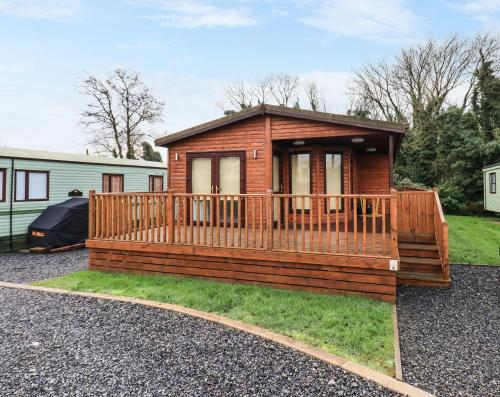 a log cabin with a large deck in a yard at Roe Deer Lodge in Newton Stewart