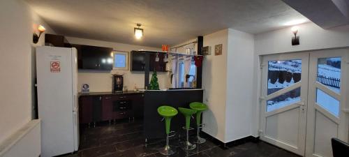 a kitchen with green stools in a room with a window at Vila Eduard in Fundata