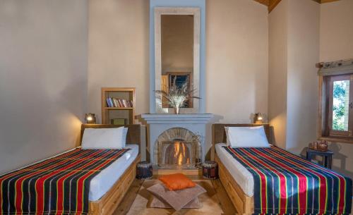 two beds in a room with a fireplace at Mary Budden Estate in Almora