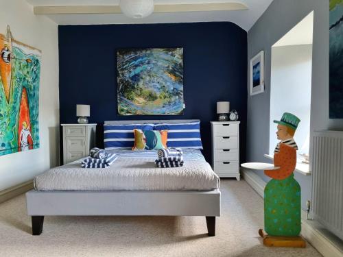 a bedroom with a bed with blue walls and a painting at An Artist's Cottage in Fishguard