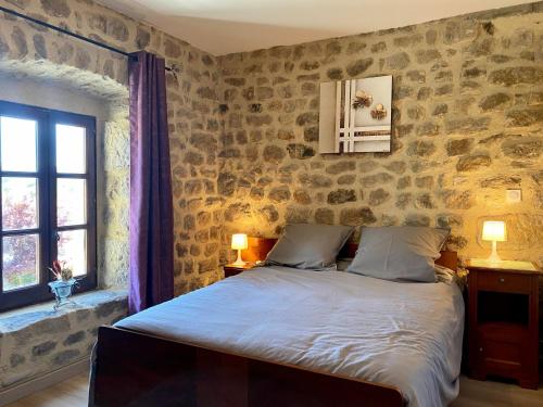 a bedroom with a bed and a stone wall at Gîte Blavozy, 2 pièces, 3 personnes - FR-1-582-57 in Blavozy