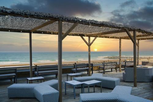 a beach bar with tables and chairs and the ocean at Baya Hotel in Capbreton
