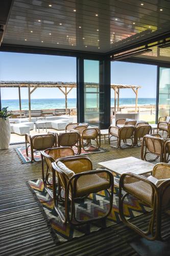 a restaurant with tables and chairs and the beach at Baya Hotel in Capbreton