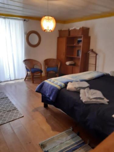 a bedroom with a bed with blue sheets and chairs at Casa Ericeira in Ericeira