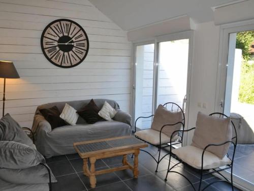 a living room with a couch and chairs and a clock at Gîte spacieux avec piscine chauffée, wifi et tennis au bord de la Loire - FR-1-590-97 in Sigloy