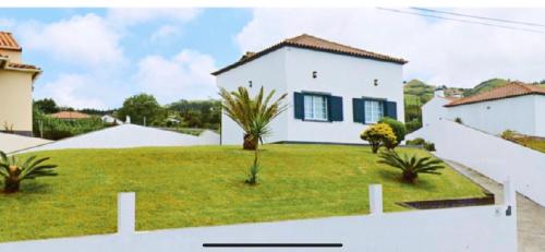 a white house with a yard with palm trees at Casa Quinta das Férias in Ginetes
