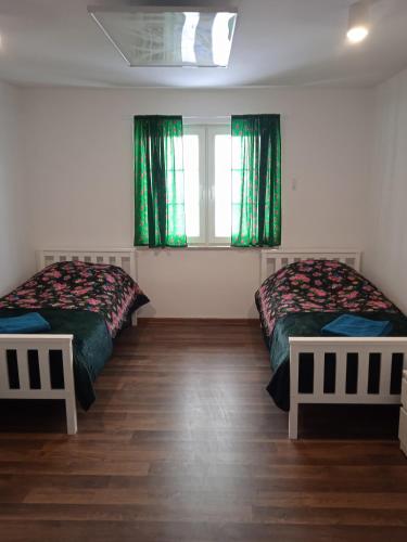 two beds in a room with green curtains at Willa Bawarczyk in Istebna