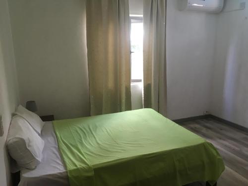 ein Schlafzimmer mit einem Bett mit einer grünen Decke darauf in der Unterkunft O soleil in Albion