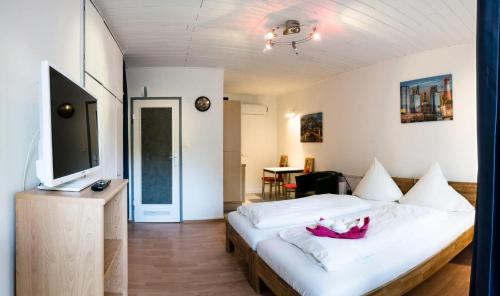 - une chambre avec un grand lit blanc et une télévision à écran plat dans l'établissement Apartment-EG-08, à Darmstadt