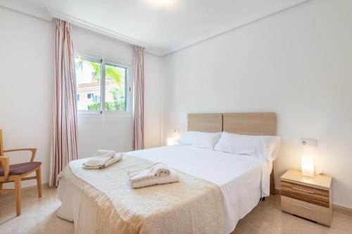 ein weißes Schlafzimmer mit einem Bett und einem Stuhl in der Unterkunft Apartment Es Mirador 2 in Cales de Mallorca