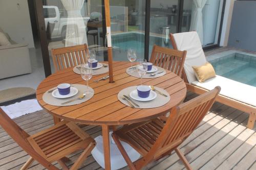 a wooden table with chairs and wine glasses on it at Fontes da Pipa by Liiv in Pipa