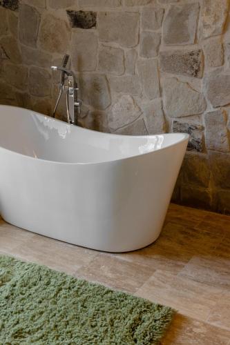 a white bath tub in a bathroom with a stone wall at Cappadocia Naif Hotel - Adults Only in Goreme