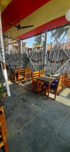a patio with wooden tables and chairs under a roof at Drishti yoga international in Patnem