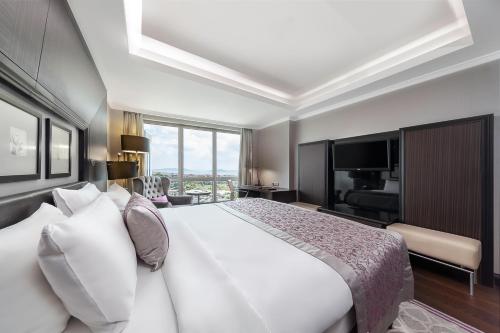 a bedroom with a large white bed and a television at Dedeman Bostanci Istanbul Hotel & Convention Center in Istanbul