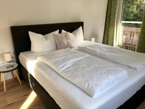 Elle comprend un grand lit avec des draps blancs et des oreillers roses. dans l'établissement Hanna`s Home, à Innsbruck