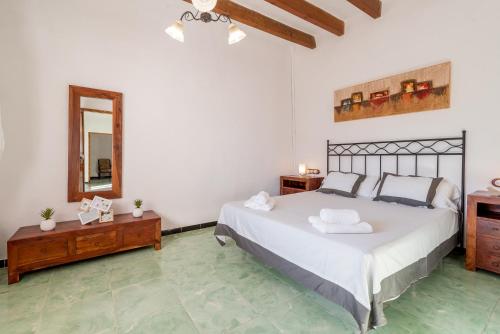 een slaapkamer met een groot wit bed en een spiegel bij Finca Ca'n Puig in Calonge
