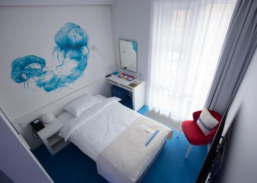 a bedroom with a bed and a red chair at Starboard Side Hotel in Moscow