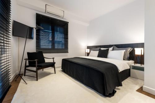 a bedroom with a large bed and a chair at Executive 2 bdr Suite in Plaka - Acropolis view in Athens